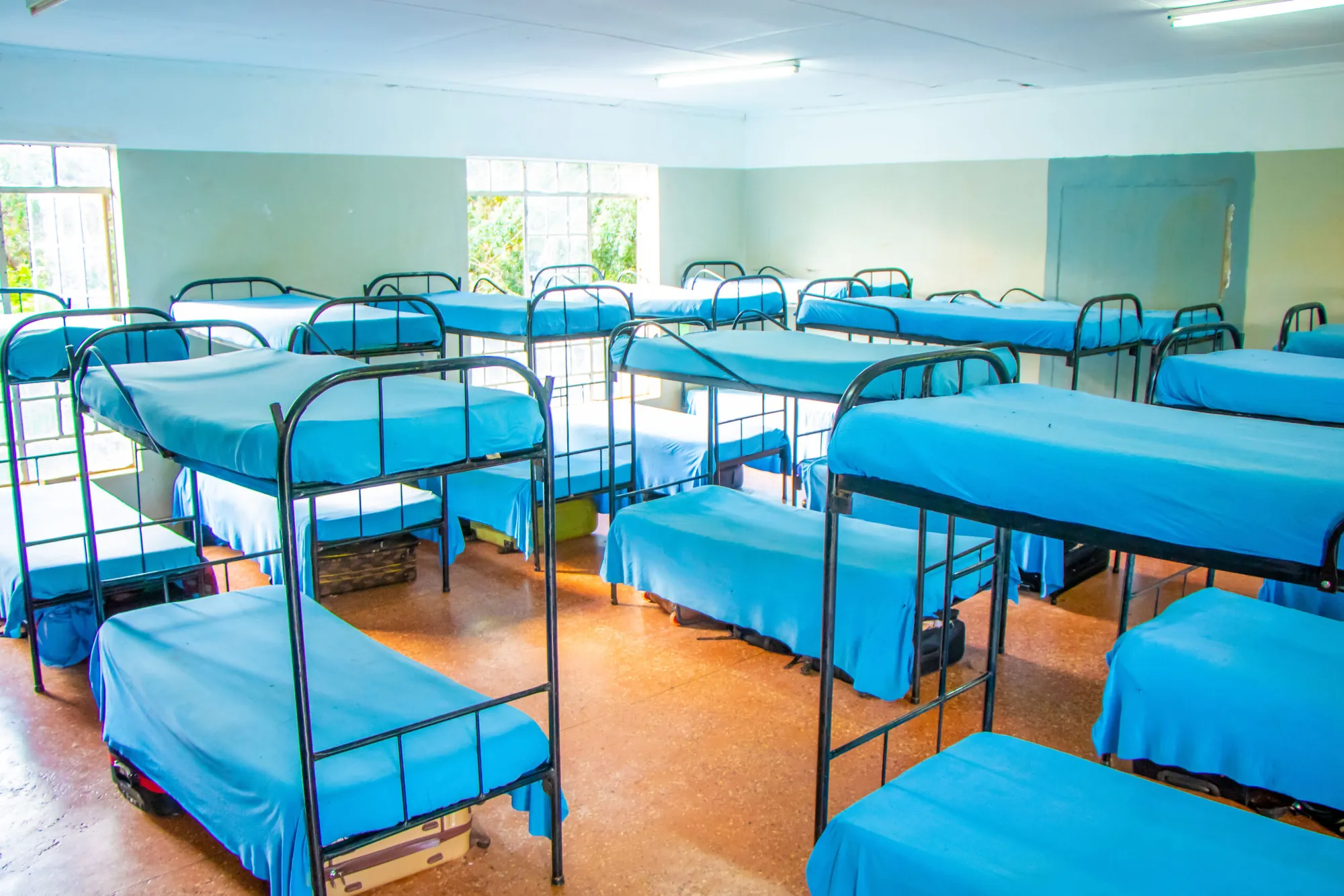 A dormitory with blue-blanketed bunk beds