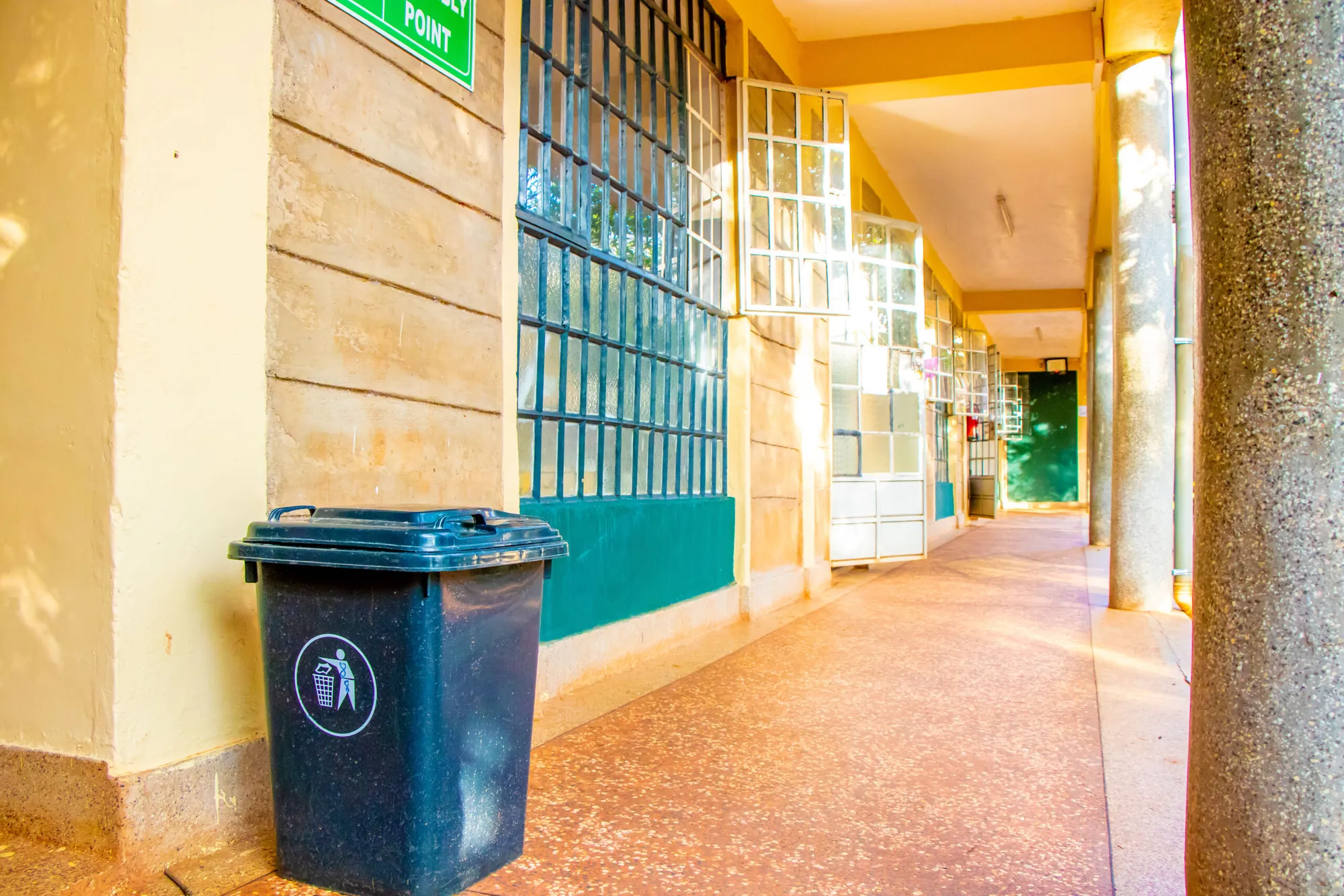 A school corridor with a dustbin and green window frames