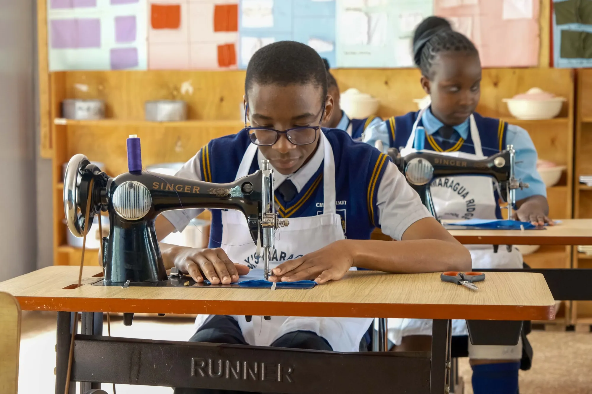 A student sewing on a sewing machine in a fashion and textiles class