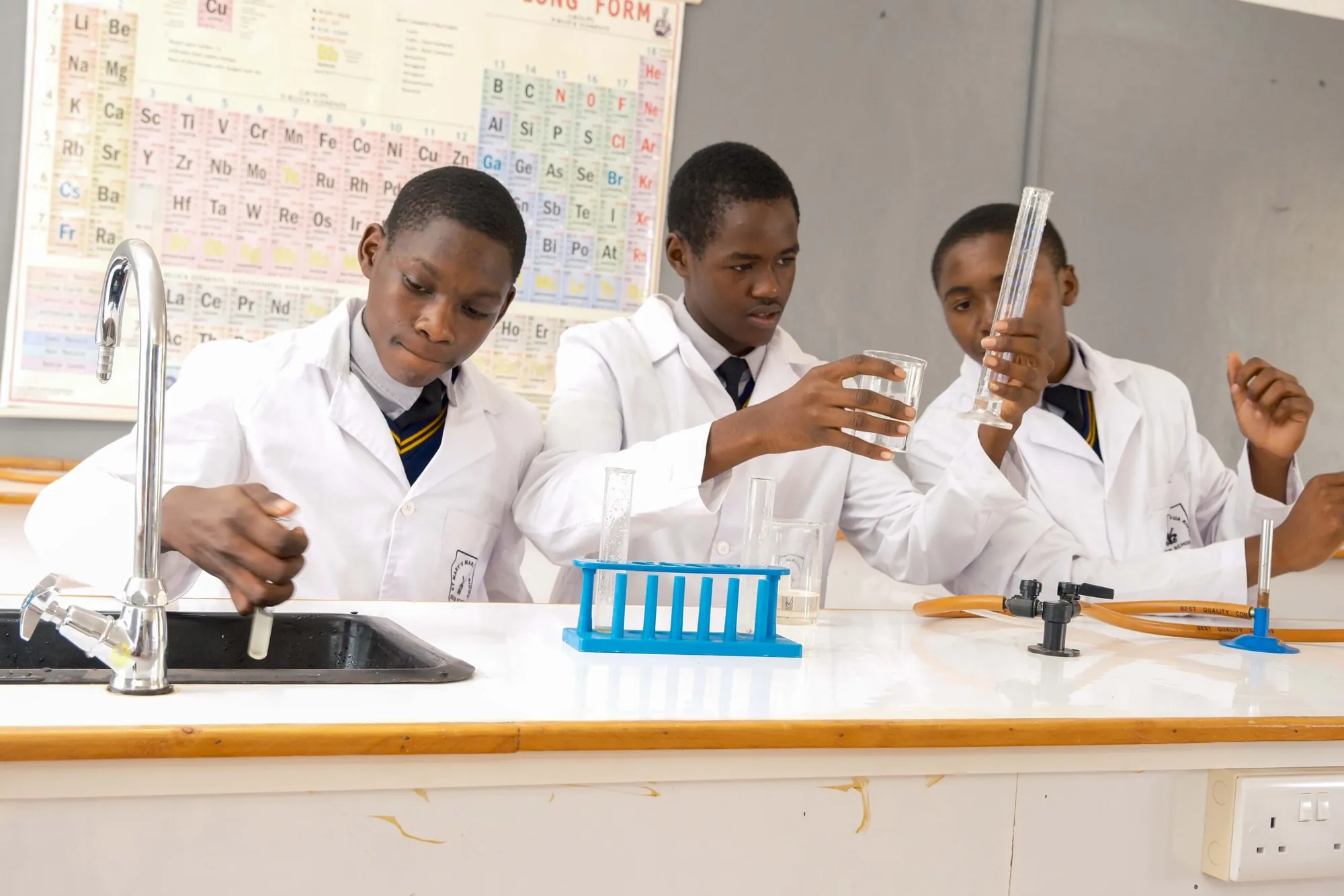 Students in white lab coats working with glassware in a science laboratory