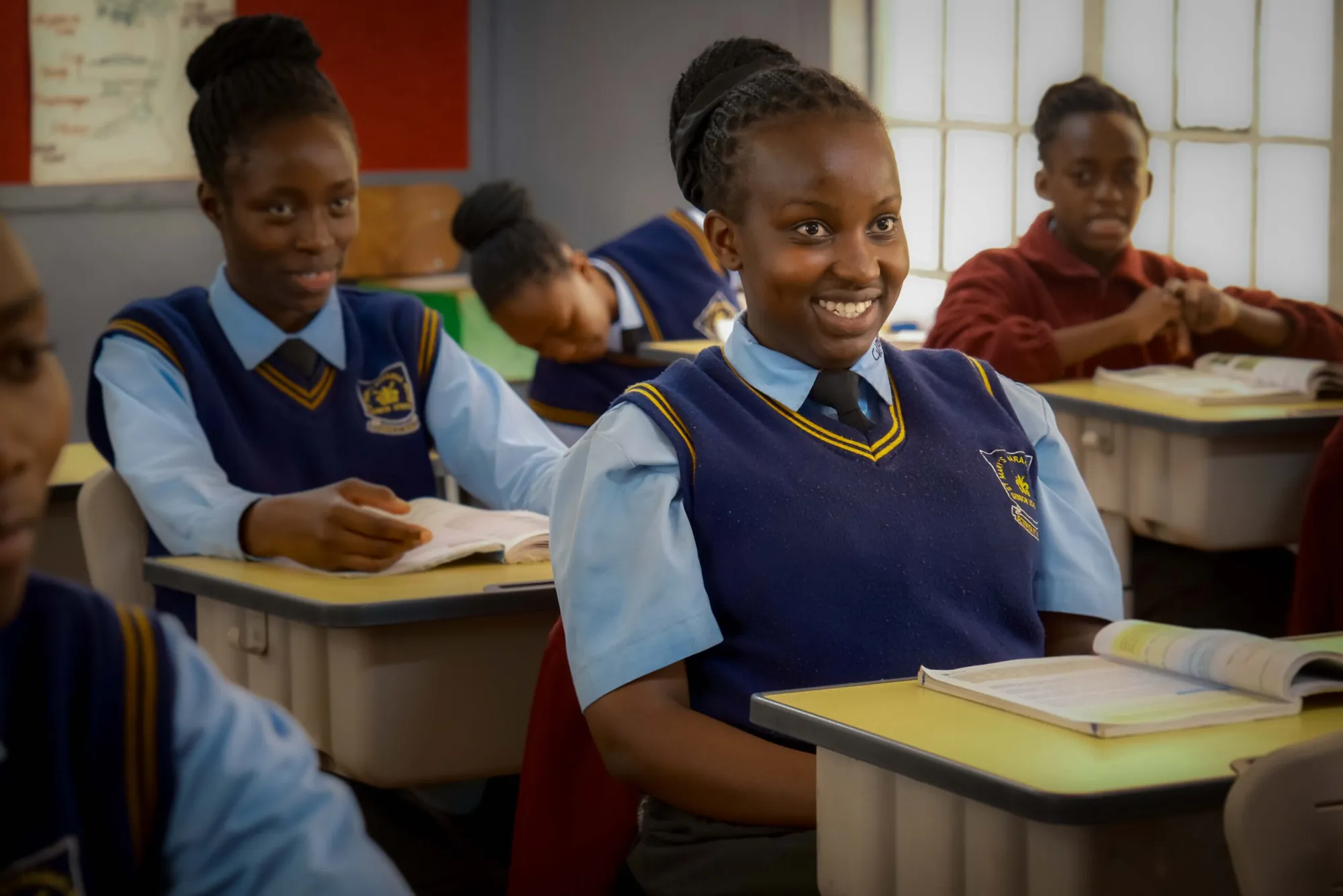 Two smiling girls seated at their desks in class